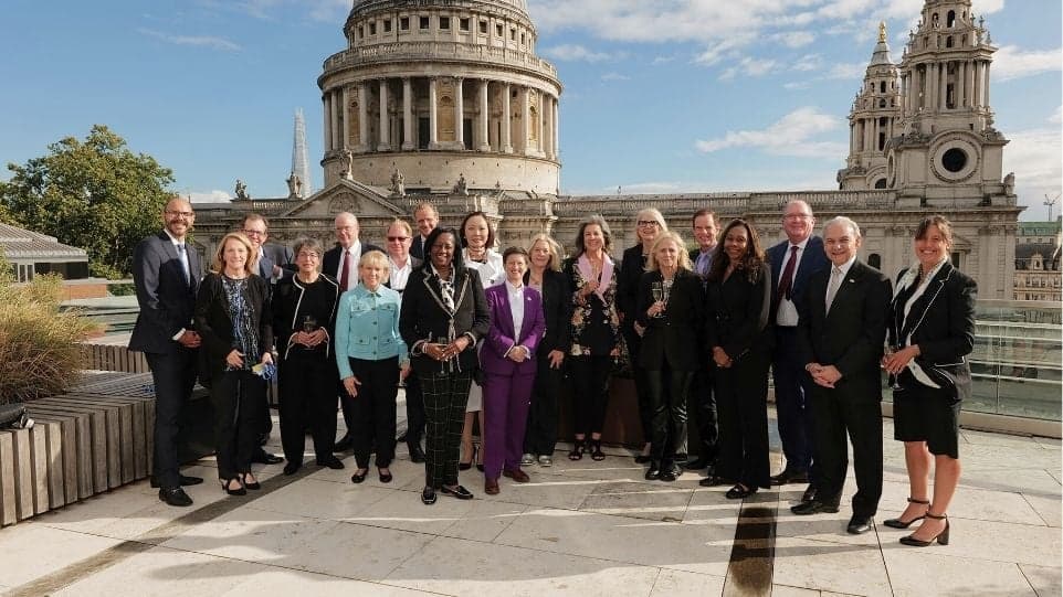 Corporate leaders posing in front of St. Paul's Cathedral on a London rooftop.